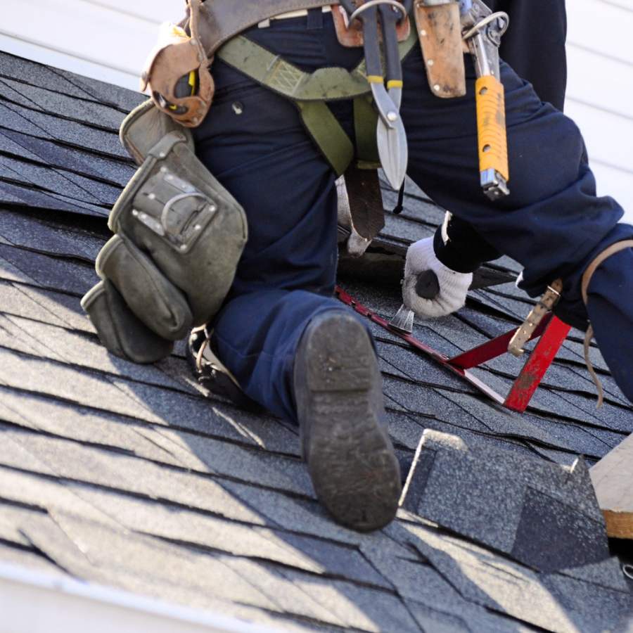 Couvreur en train de travailler sur un toit avec son matériel et ses équipements